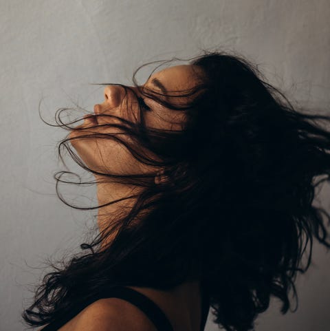 this evocative portrait captures a woman with her head thrown back, hair swirling in the air, as though carried by an invisible breeze. her face is partially obscured, allowing the movement of her hair and the soft lighting to create a sense of freedom and abandon. the image speaks to the beauty of letting go and being present in the moment, where time stands still, and everything feels weightless. a delicate interplay of light and shadow adds depth and texture, making this minimalist yet powerful visual resonate with emotion.